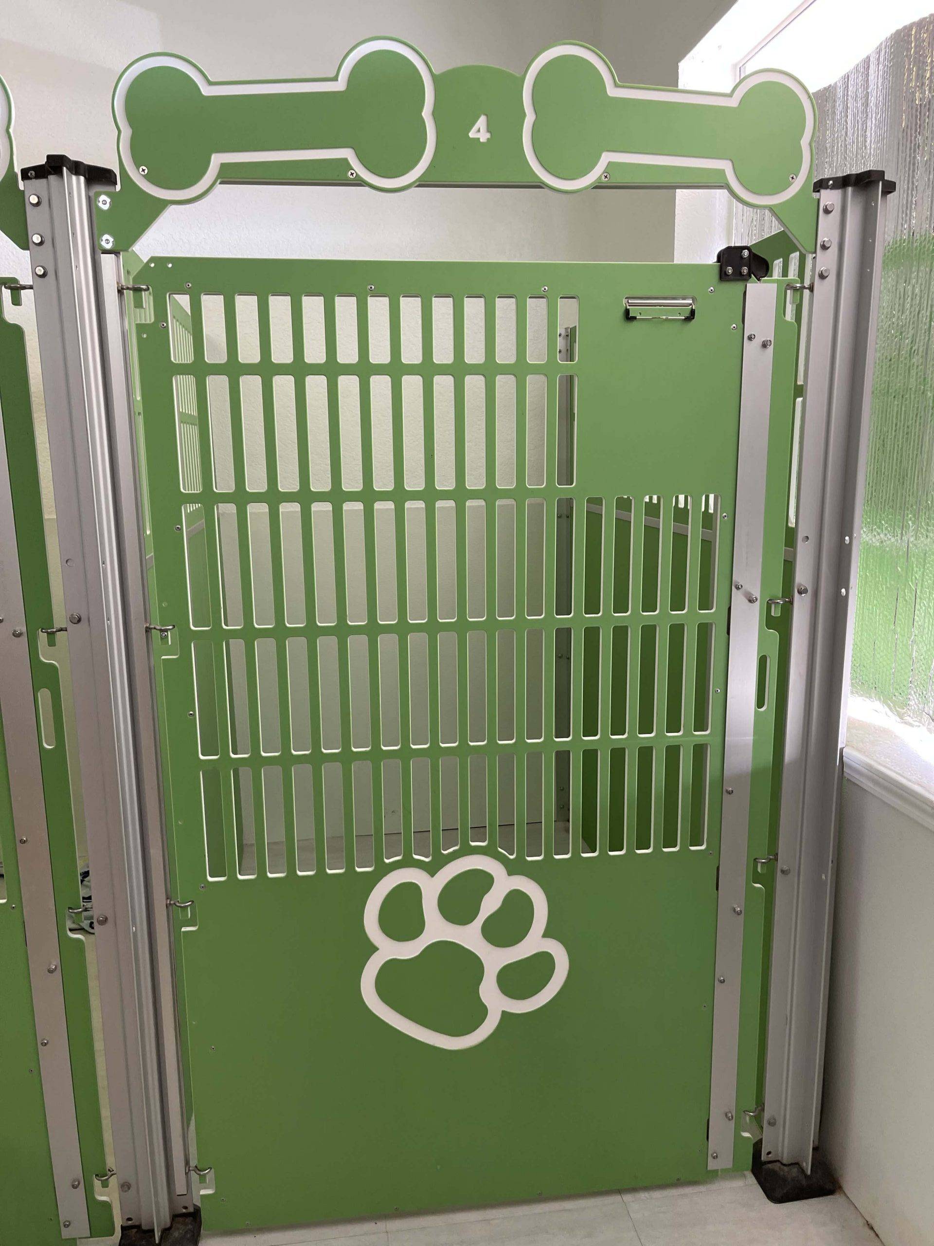 A premium pet services green dog kennel with paw prints on it.